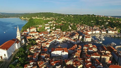 Flight over old city Piran in Slovenia, aerial panoramic view with old houses, roofs, St. George's Parish Church, Tartini Square, fortress and the sea. 
