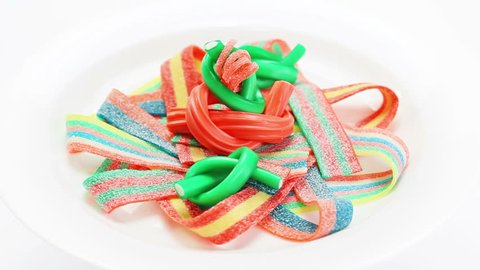 Colorful licorice gummy sweets rotating on a white plate  