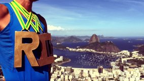 First place athlete wearing RIO gold medals message standing above a scenic skyline overlook in Rio de Janeiro, Brazil 