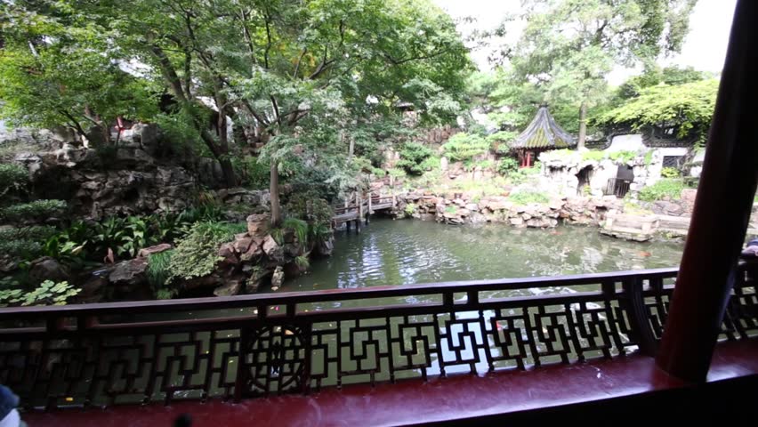 Two women and man look at beautiful pond in China garden