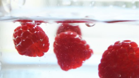 Raspberry falling in the glassware with water. Full HD 1080p high definition