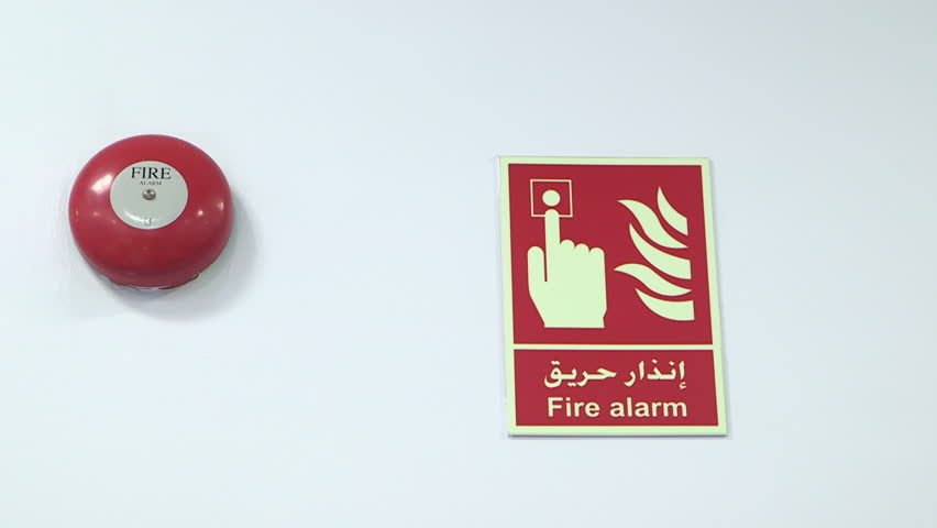 Fire Hazard Equipment. Tilt-up from a 'Fire Alarm' sign in English and Arabic and a red fire alarm on a white wall. (Abu Dhabi, UAE-2013) Royalty-Free Stock Footage #18789281