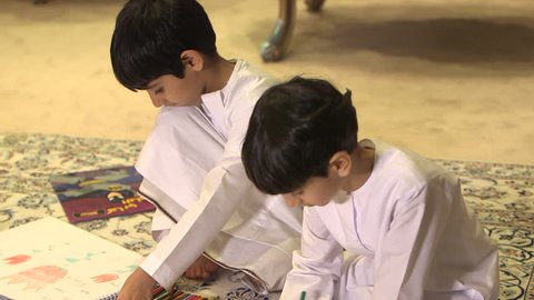 Abu Dhabi, UAE - CU tilt-up onto two Emirati boys playing with colouring pencils while sitting on a carpet. (Abu Dhabi, UAE-2013)