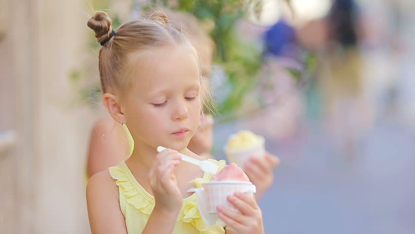 Adorable little girl eating ice-cream outdoors at summer. Cute kid ...