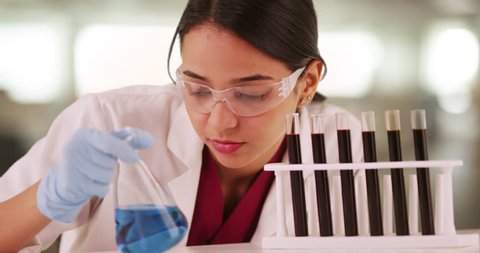 Latino scientist looking at liquids in vials
