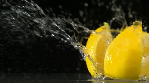 Slo-motion lemon  falling into wedges against black drop