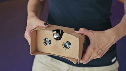 Young curly woman using Virtual Reality Glasses. Woman's hands holding cardboard. Virtual reality mask. VR. Close up shot Video de stock
