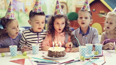 children blowing out candles on birthday cake