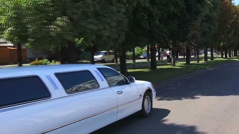white limousine rides on the road in the summer