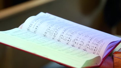 SALT LAKE CITY, UT - June 30, 2016: A parishioner holds a hymn book open.