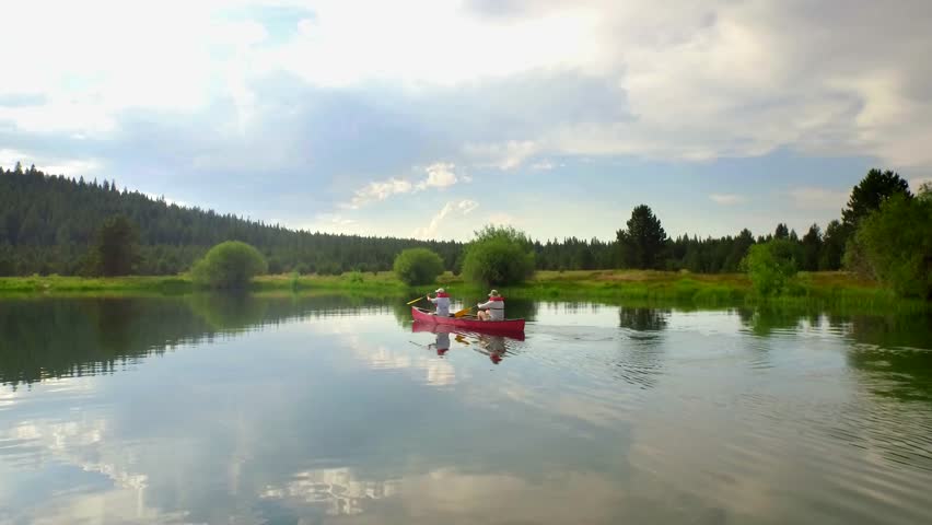Couple kayaks next to Oregon mountainside in sunset