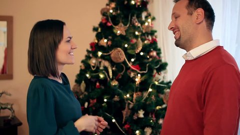 Man giving gift to woman in front of Christmas tree Stock Video