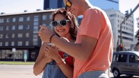 summer vacation, technology, augmented reality and people concept - happy teenage couple with smartphones playing game or shooting video in city