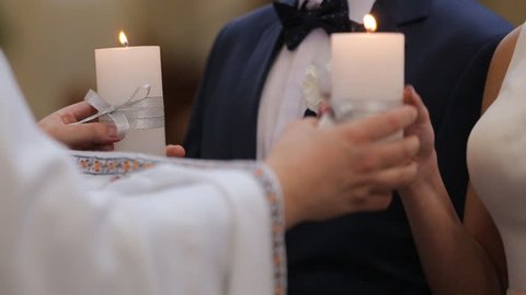 young couple in the church holds wedding candles