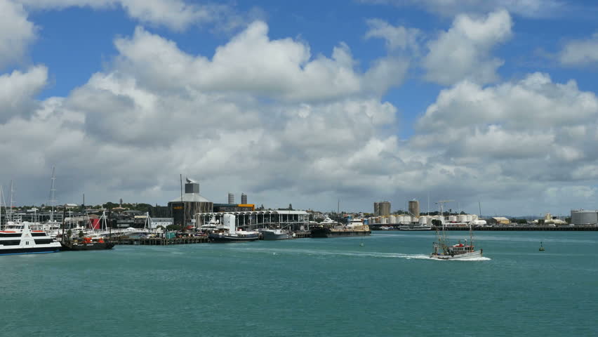 Clouds rise over Auckland Bay as a fishing boat heads out from the docks.