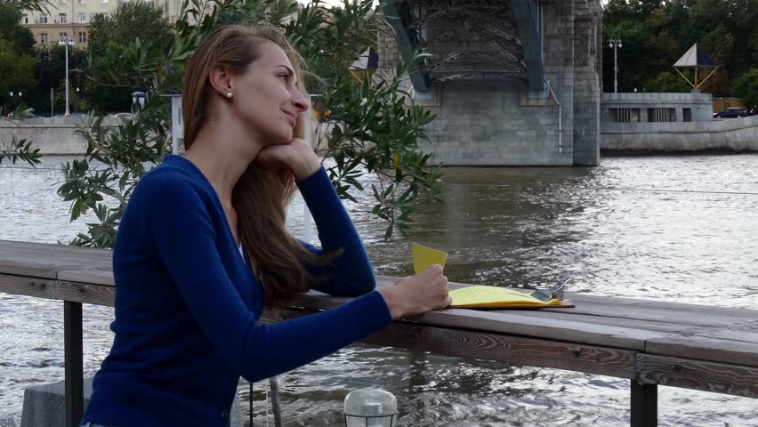 Young happy woman reading menu in street cafe autumn day