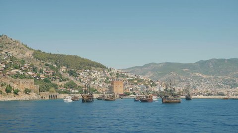 ALANYA, TURKEY - JULY 10, 2016: Pirate ship on the water of Mediteranean sea, near the Ruins of Ottoman fortress. Ship traveling around Alanya castle