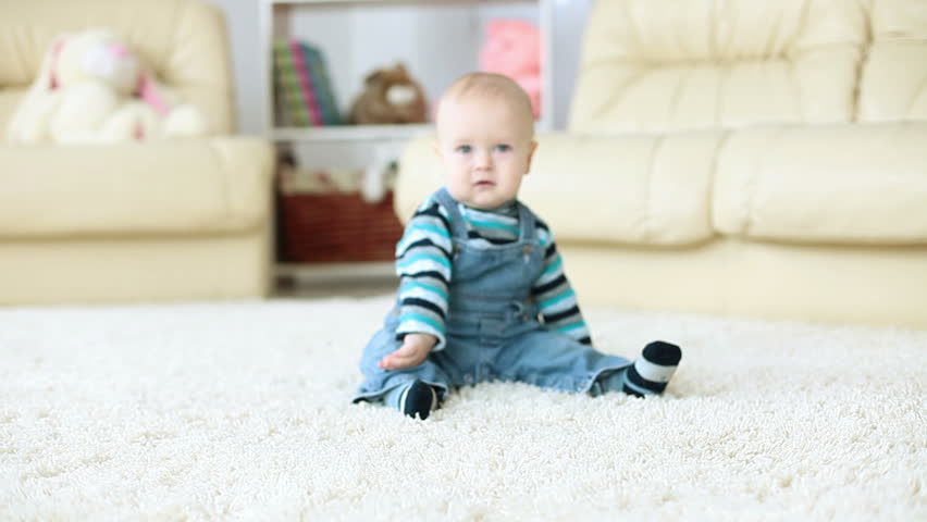 Baby boy sitting on the carpet in the room