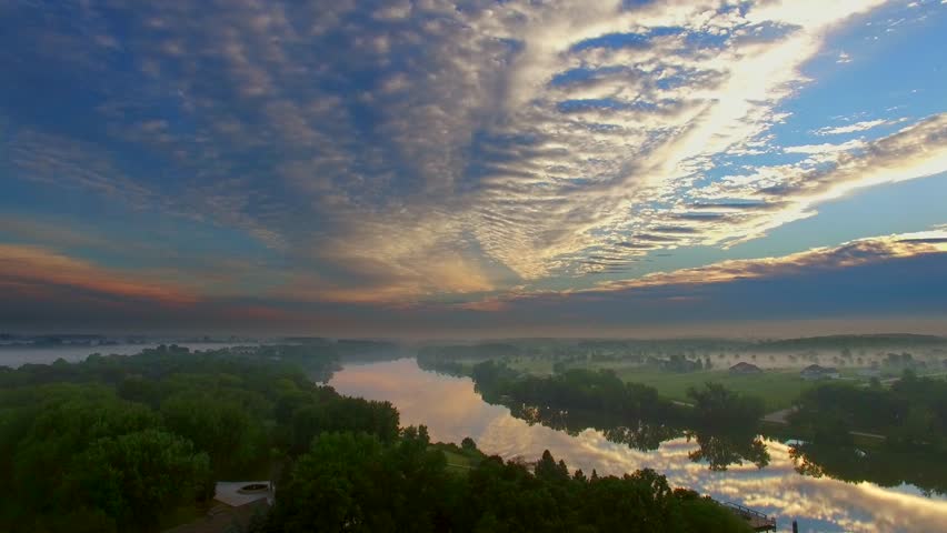 Spectacular dawn sky reflected in still waters with foggy landscape, aerial view.
