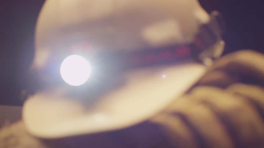 Camera Pans Across Mining Helmet and Headlamp Sitting on Leather Work Gloves and Rocks