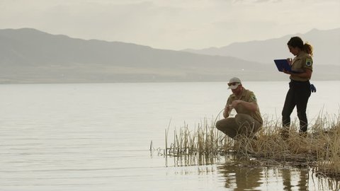 Wide shot of park rangers collecting water sample from lake / Vineyard, Utah, United States Adlı Stok Video