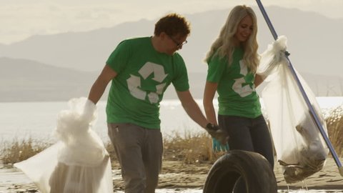 Medium panning shot of volunteers carrying garbage from lake / Vineyard, Utah, United States