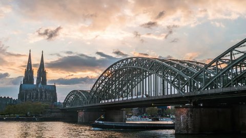Sunset timelapse of Cologne Cathedral and Hohenzollern Bridge, Germany. Video with moving clouds, sunset lights, and night illumination.