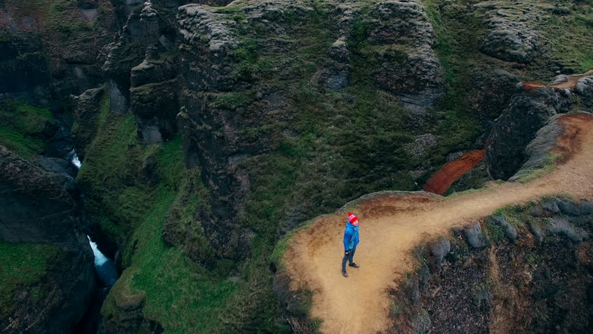 Aerial view of man with raised hands up feeling freedom while standing at Fjadrargljufur canyon in Iceland