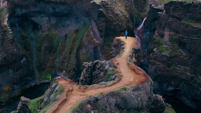Aerial view of man with raised hands up feeling freedom while standing at Fjadrargljufur canyon in Iceland