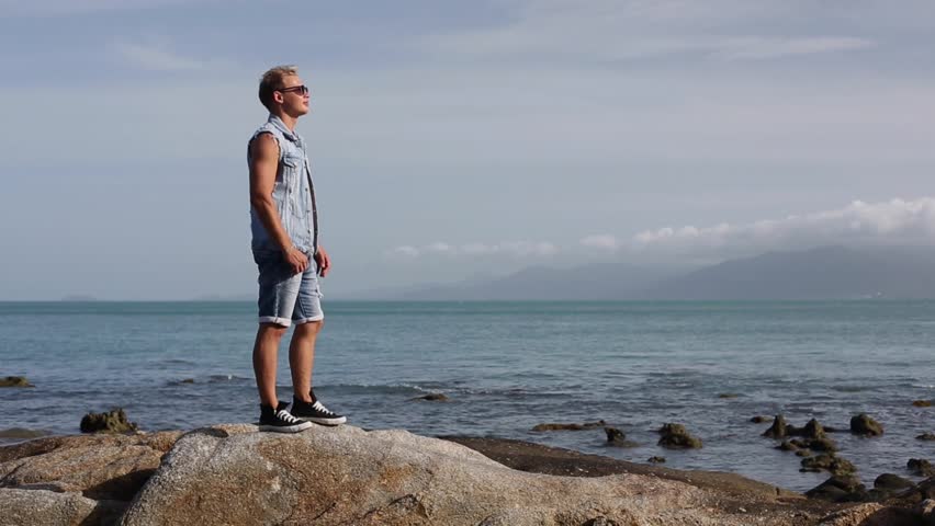 Serious cool guy dancing happy on the sea