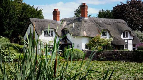 old English thatched house in front of mill pool - Badger, Shropshire, England: August 14th 2016
