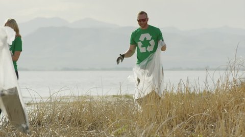 Wide panning shot of volunteers collecting garbage at lake / Vineyard, Utah, United States