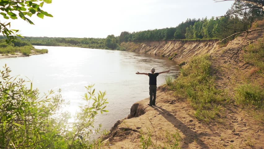boy stretched out his arms to the sides by the river slow motion video