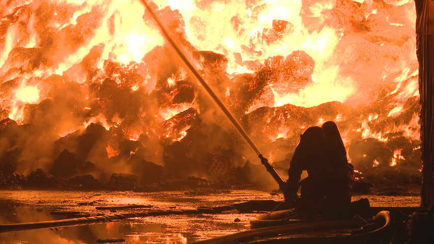 Fireman fighting a large Industrial fire with a water canon