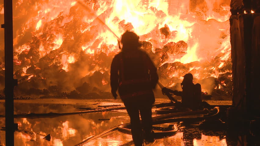 Firemen at a large fire change the head on a fire hose