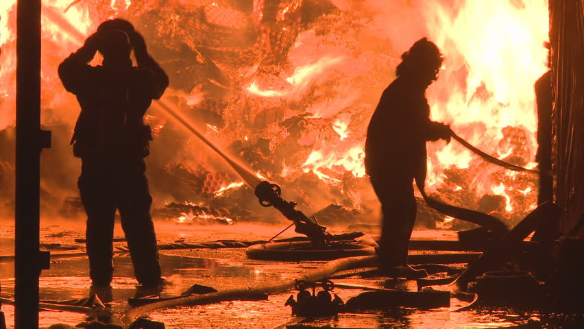 Firemen fighting a large nighttime fire.