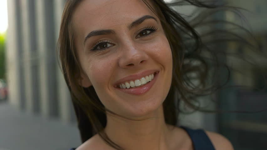 Portrait Wonderful smiling woman with a lovely look and natural make up looking smiling at camera and the wind moving her hair Real, city, people, lifestyle, , confidence, person, , face successful 