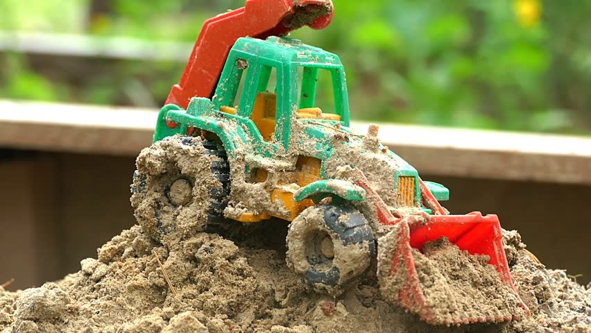 Toy tractor in the sandbox slow motion video