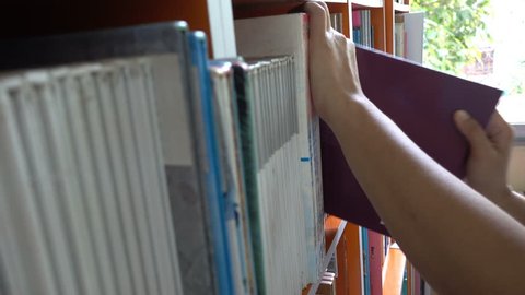 focus of woman hand, put a book on bookshelf at library