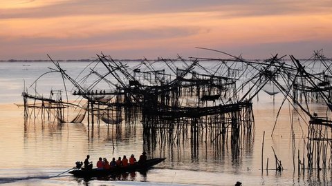 Traditional fishermen net fishing in the lake at sunrise time. Thai style fishing trap in Pak Pra Village, Phatthalung, South of Thailand. 