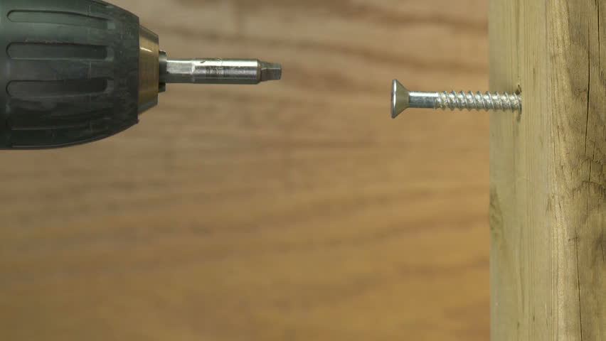 Turning a screw into a two by four with power drill 