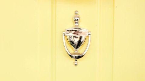 Classic door knocker on yellow home entrance 