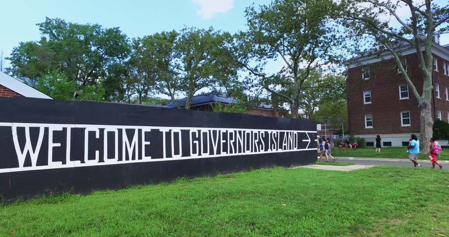 Tourists and visitors walk past the welcome sign on their visit to Governors Island, New York.  	