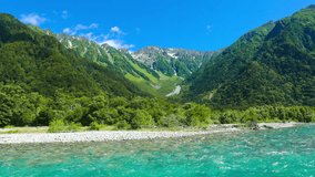 Zoom out time-lapse of beautiful turquoise, clear glacial river water and cloud movement on Mount Hotaka during summer day in the northern Japanese Alps nature town of Kamikochi in Nagano 4k 30fps
