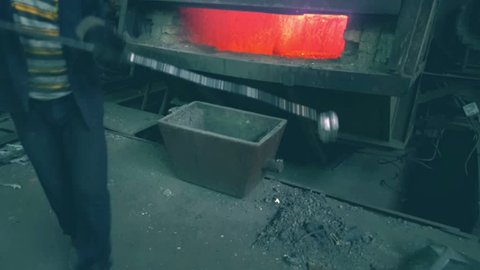 Steelmaker takes a sample of metal from the melting furnace in the foundry