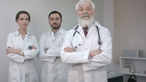 Three confident clinicians in white coats looking at camera.