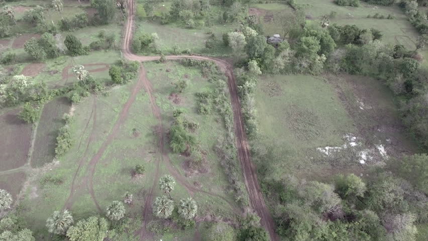 Aerial vertical shot looking down over a zigzag path road through green fields