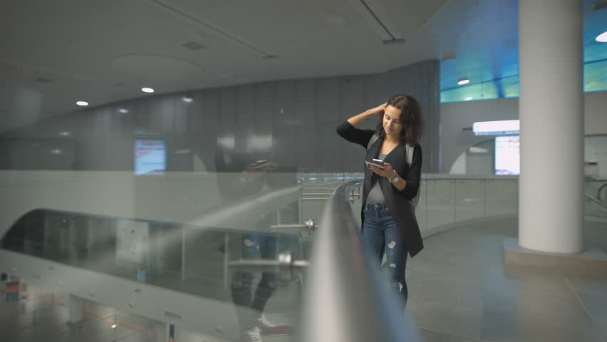 Young woman chatting on cell telephone with friend at the airport,