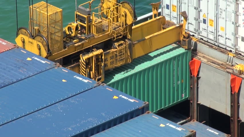 A gantry crane or portainer is stacking containers on a large ship, while passing a truck, it is night in the Port of Kaohsiung the largest harbor in Taiwan.