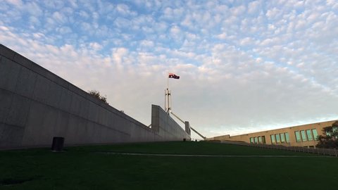 The flagpole is revealed at The Australian Parliament House in Canberra as the 4k shot tracks up the grass hill away from the iconic curved wall. 